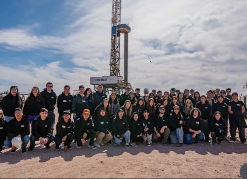 Grupo de jóvenes egresados frente a un equipo de perforación en Vaca Muerta