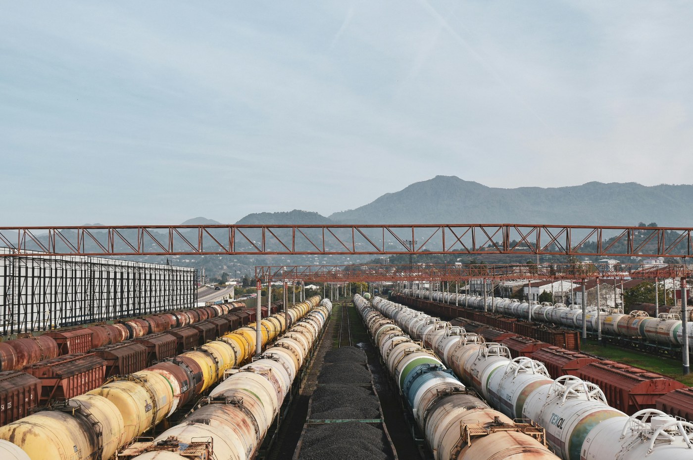 Vagones cisterna de tren en una terminal de carga, con montañas de fondo
